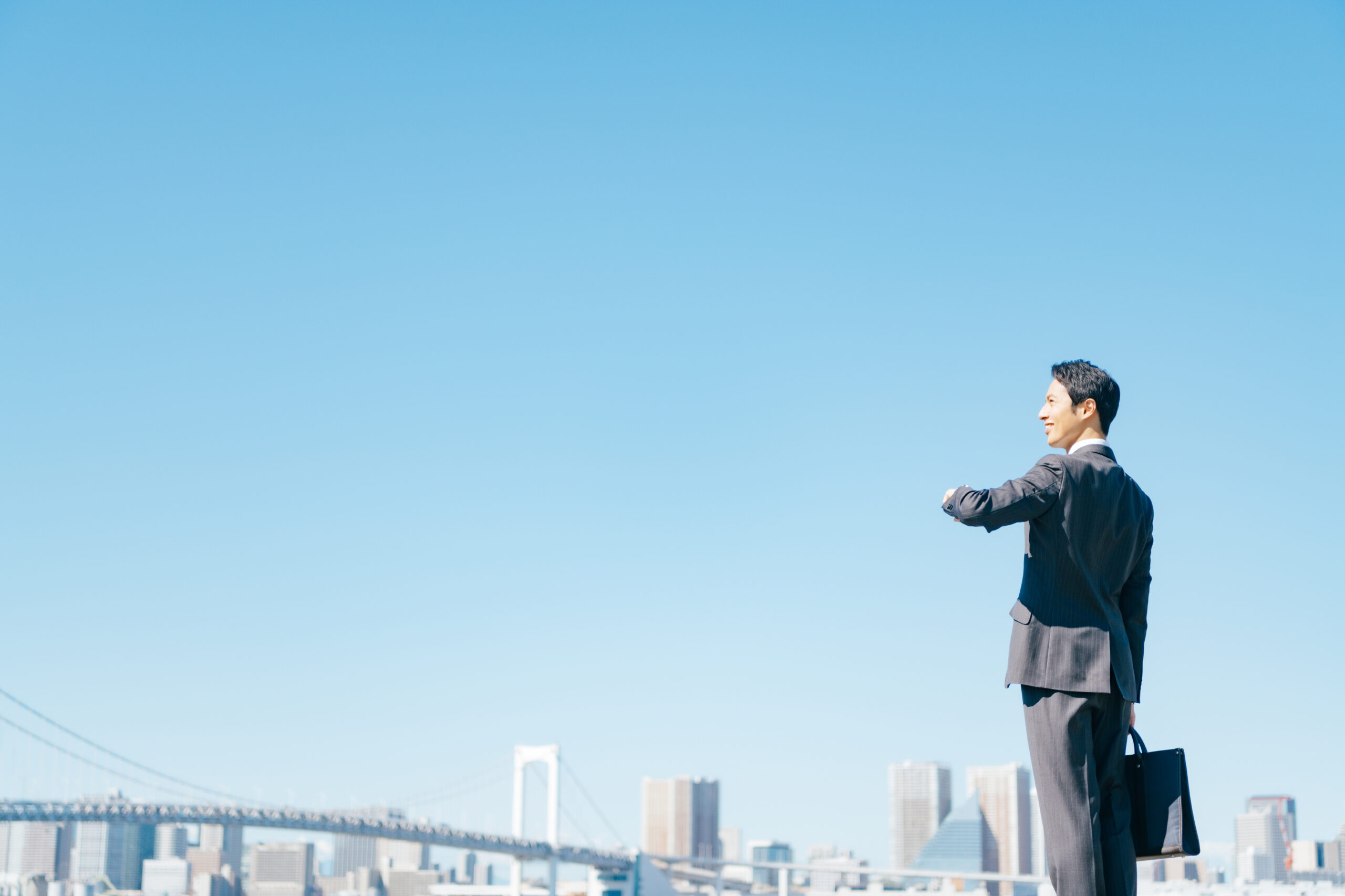 都市を背景に時間を確認するビジネスマン｜効率的に働く個人事業主のイメージ